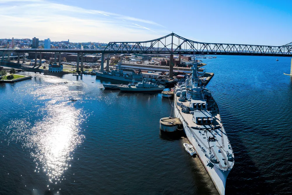 Aerial view of Battleship Cove and the Braga Bridge over the Taunton River in Fall River, with the city skyline behind